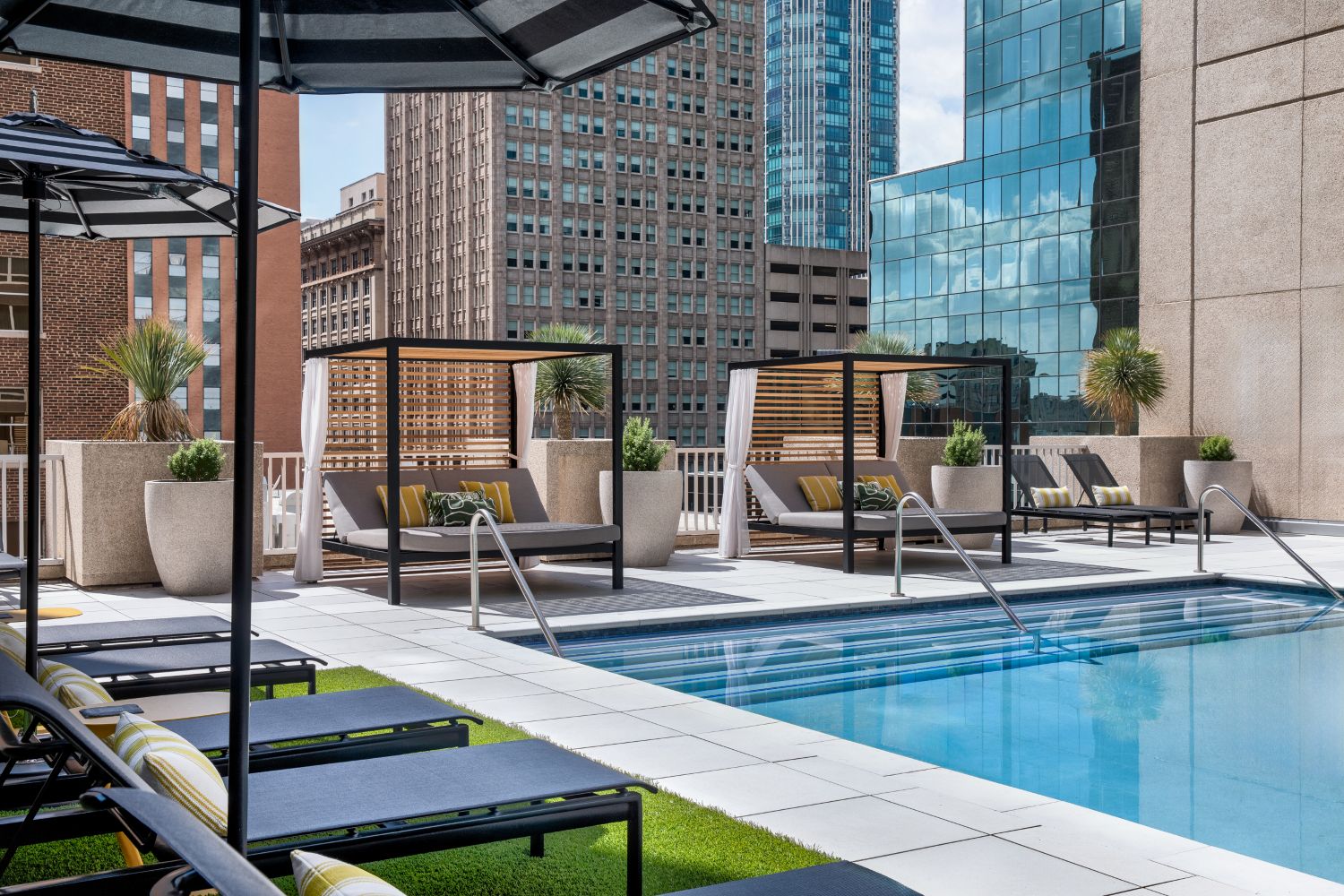 a pool with lounge chairs and umbrellas in a city